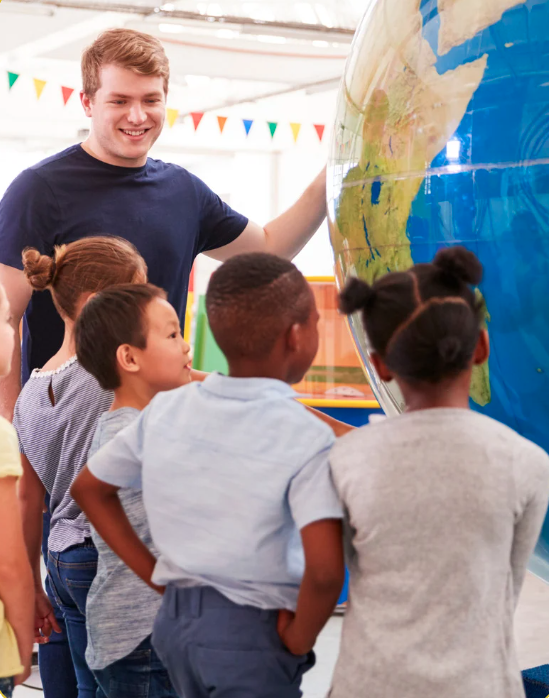 Teacher with students looking at a globe